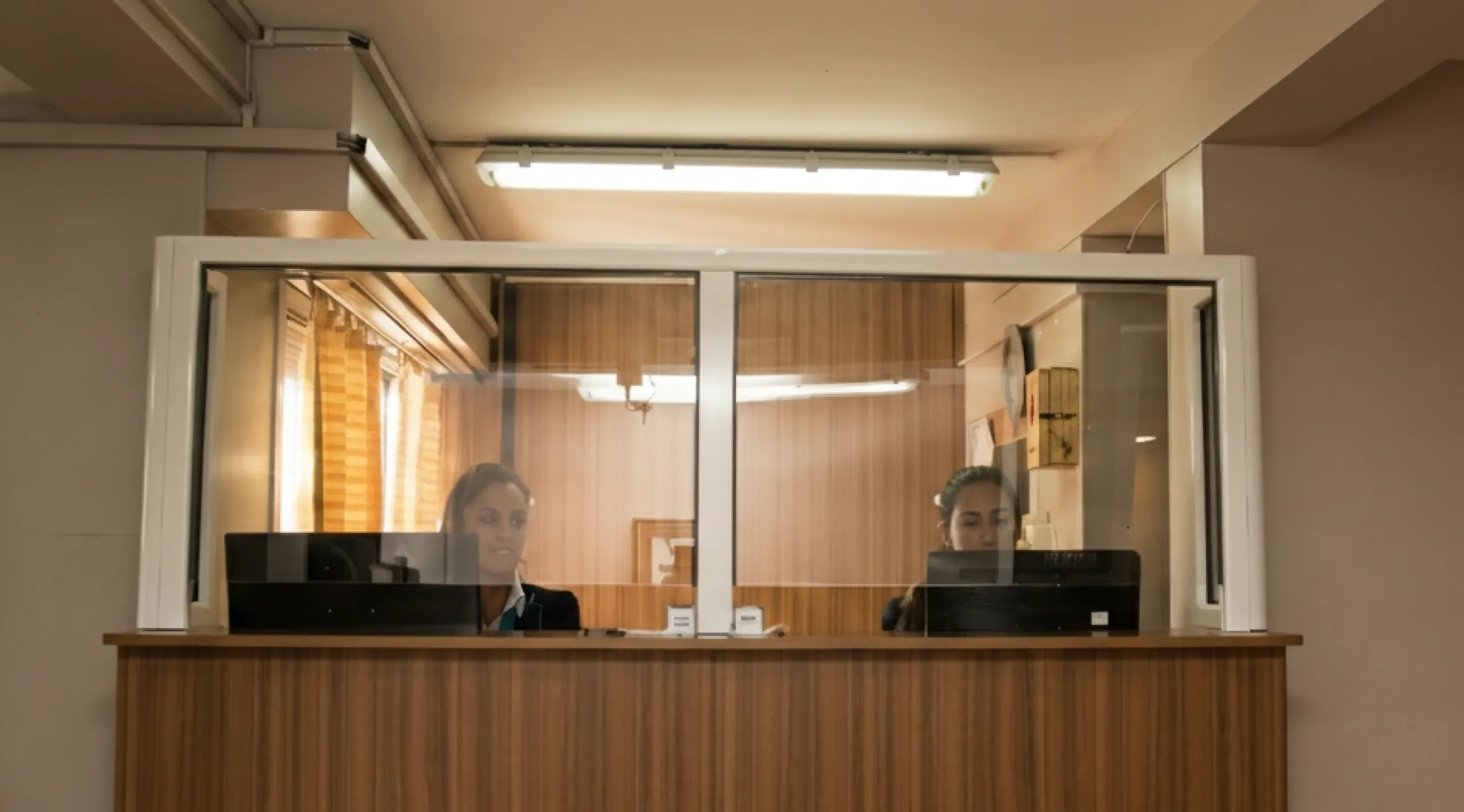 Imagen de ventanilla de recepción para solicitud de turnos con dos empleadas atendiendo.